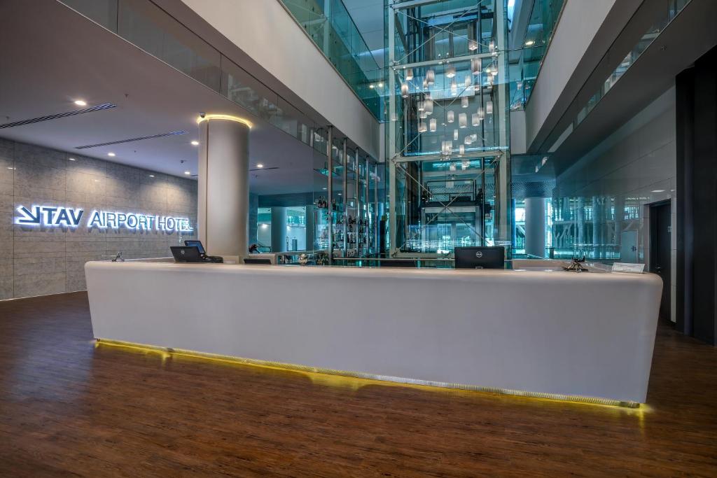 a lobby with a large white reception desk in a building at TAV Airport Hotel Izmir in Izmir