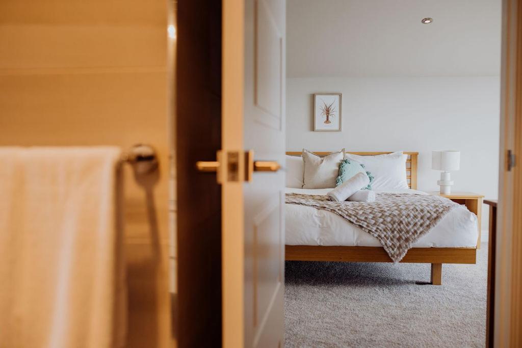 um quarto com uma cama com lençóis brancos e almofadas em Haven on James em Bicheno