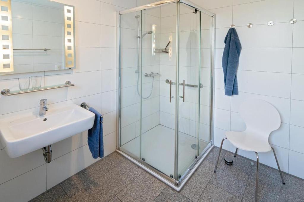 ベンサージールにあるFerienhaus Friesenkroneのガラスのシャワーと洗面台を備えたバスルーム