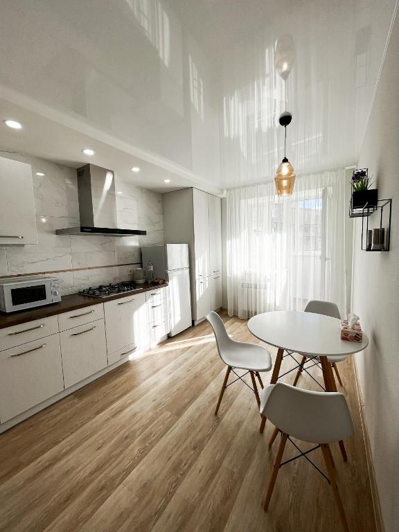 a kitchen with a table and chairs in a room at Світлі апартаменти в самому Центрі біля Корпусного парку - Мережа HELEN in Poltava