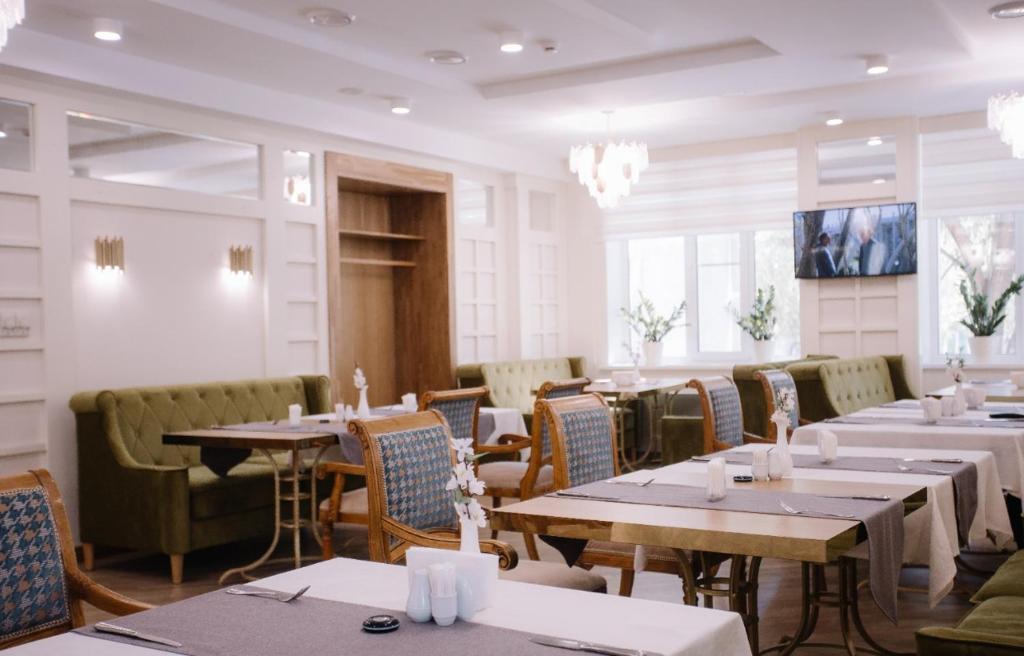 a restaurant with tables and chairs in a room at Hotel Dastan Aktobe in Aktobe