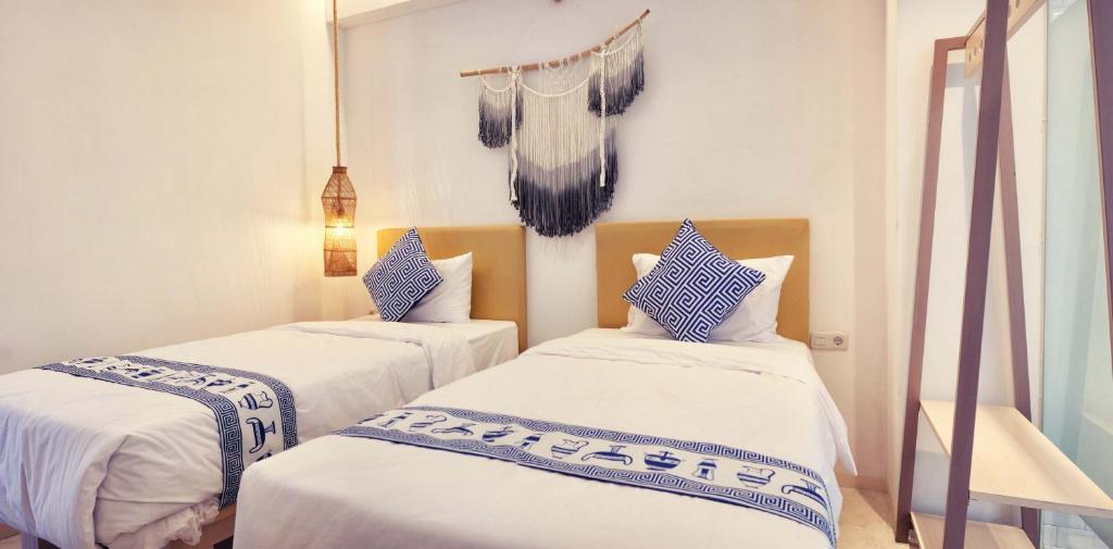 two beds with white sheets and blue pillows in a room at Little Mykonos in Bandung