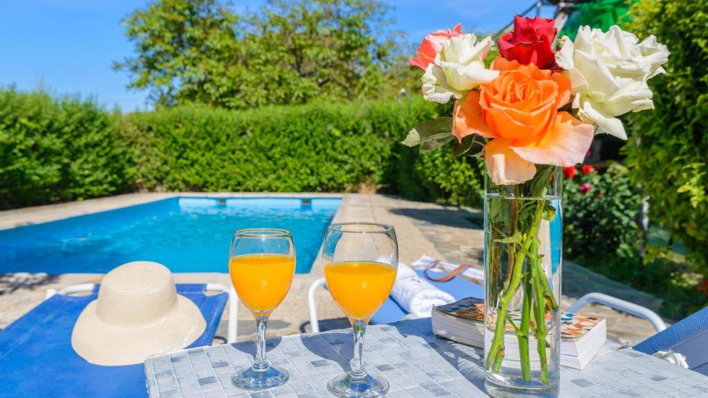 une table avec deux verres de jus d'orange et un vase de fleurs dans l'établissement Casita Mónica Órgiva by Ruralidays, à Órgiva
