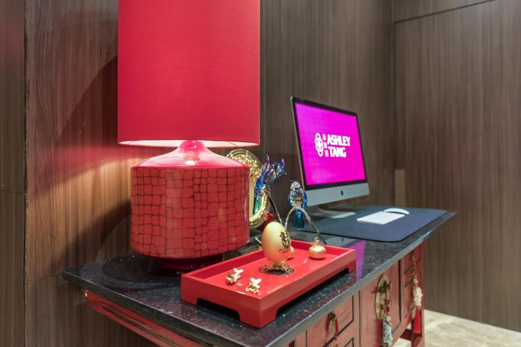 a desk with a computer and a red lamp on it at Ashley Tang Menteng Jakarta in Jakarta