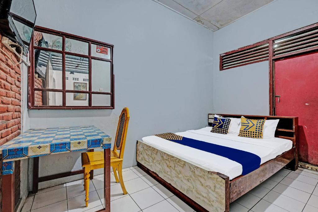 a bedroom with a bed and a desk and a window at SPOT ON 91915 Homestay Superman in Yogyakarta