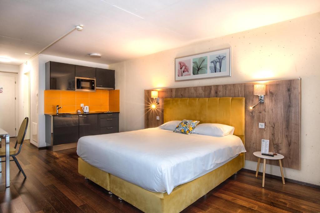 a bedroom with a large bed and a kitchen at Hotel Residence Loren - contact & contactless check-in in Uster