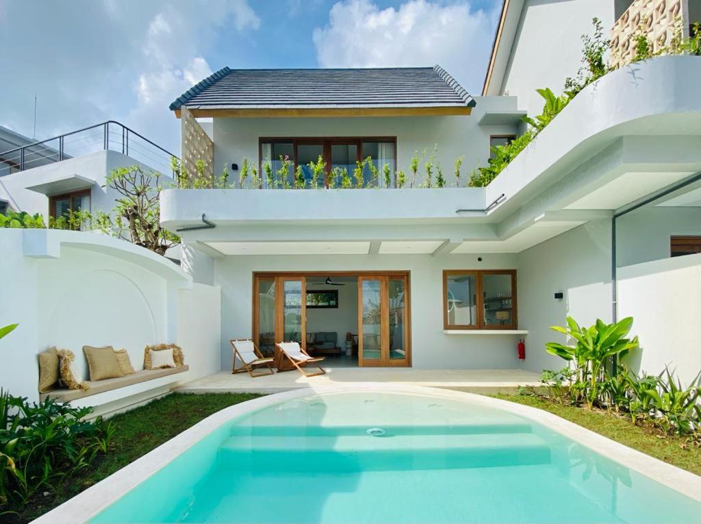 a villa with a swimming pool in front of a house at Shoreline Villas Bingin in Uluwatu