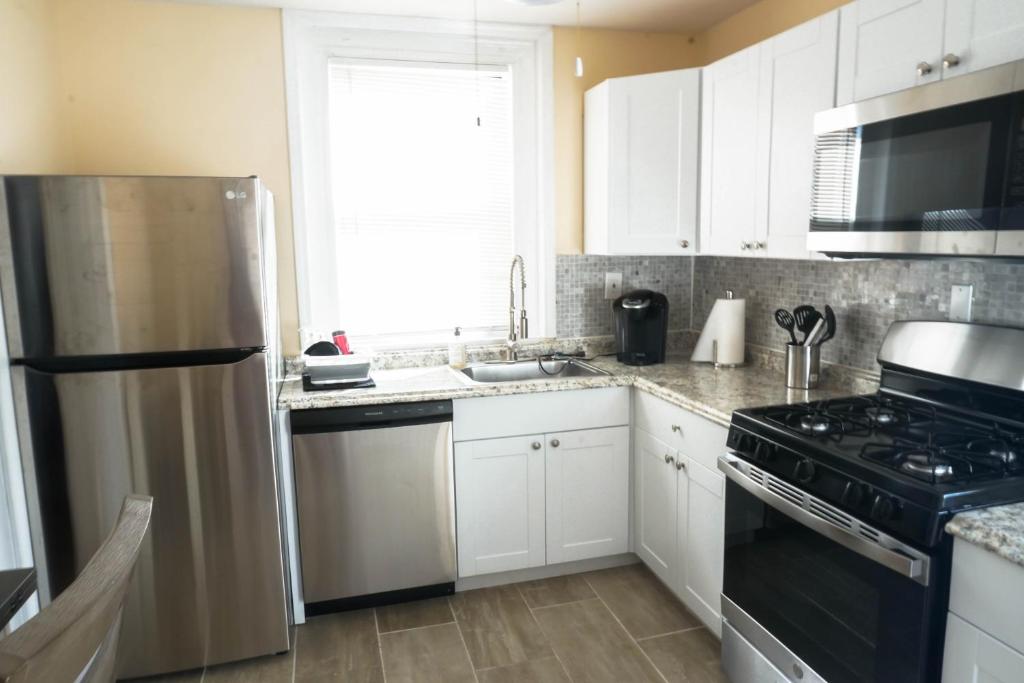a kitchen with white cabinets and a black refrigerator at Lincoln Manor - Newly Renovated, 1mile from PHL Airport and Sports Stadiums in Prospect Park