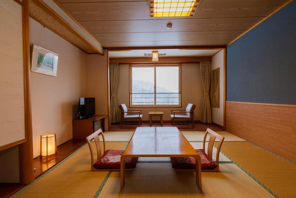 a dining room with a table and chairs and a window at Kyukamura Nyuto-Onsenkyo in Senboku