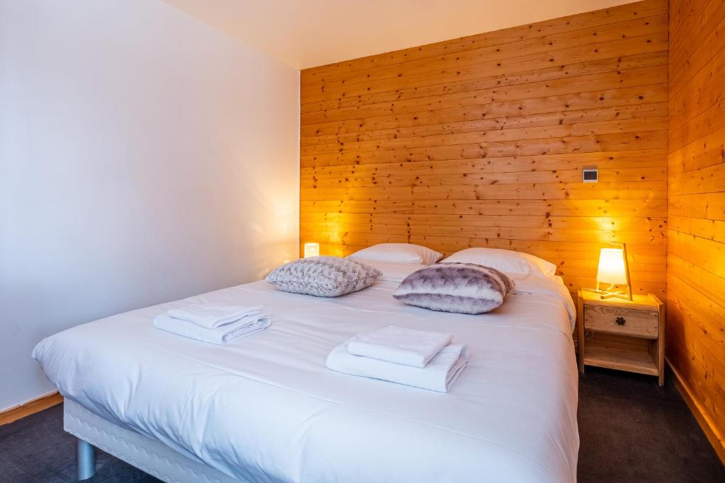 1 dormitorio con cama blanca y pared de madera en La Chapelle Aux Pieds Des Pistes en Chamonix-Mont-Blanc