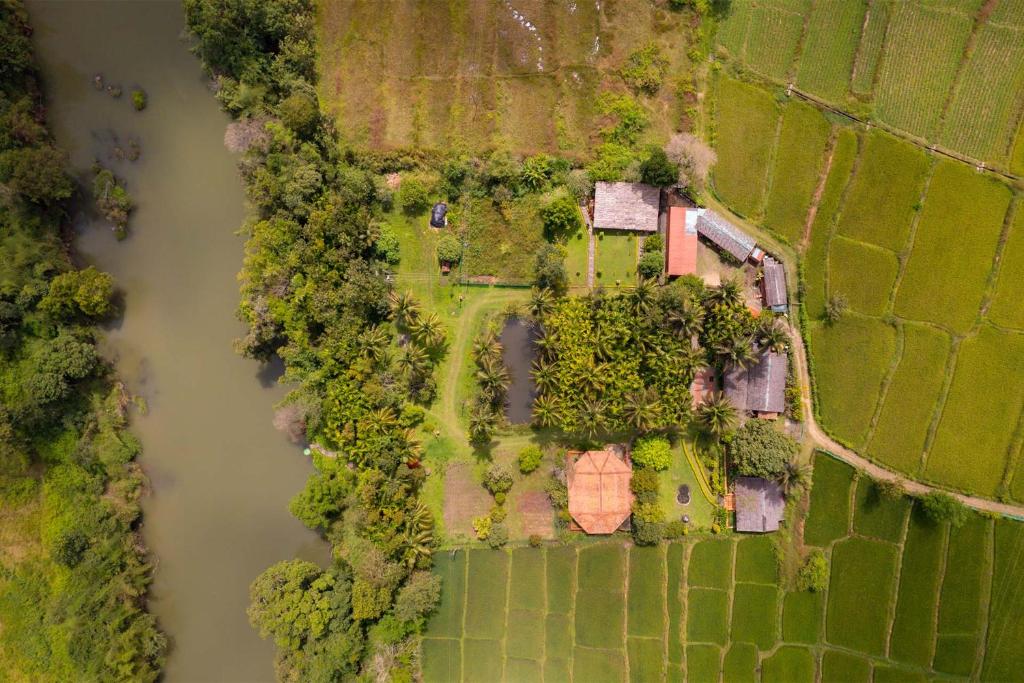 an overhead view of a field with trees and a house at StayVista at Firefly By The River with Breakfast in Kushālnagar