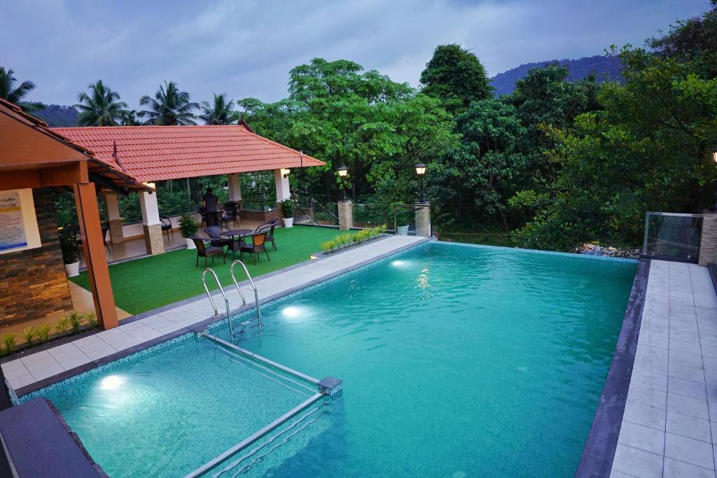 a swimming pool in a yard with a house at Athirappilly Rainland Resort in Athirappilly