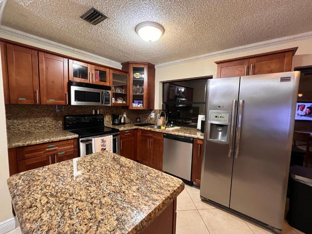 cocina con armarios de madera y nevera de acero inoxidable en Entire Single Family home 3 bed 2 bath in water front big cozy back yard view en Coconut Creek