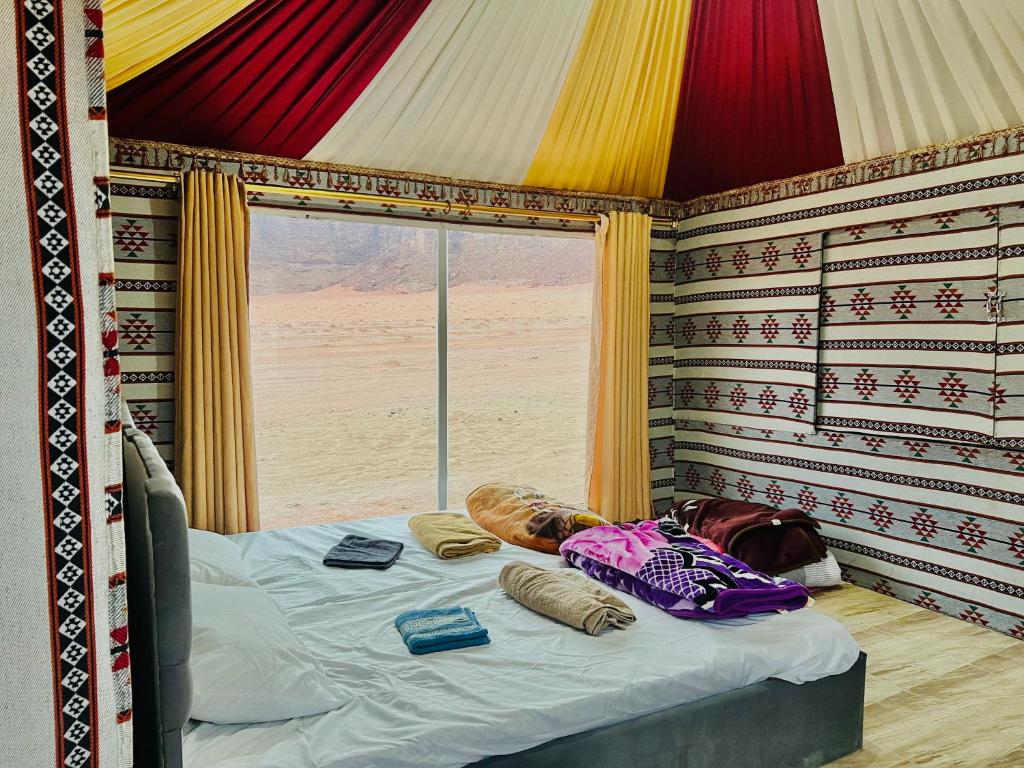 a bedroom with a bed in a room with a window at Wadi Rum Cave Camp &Jeep Tour in Wadi Rum