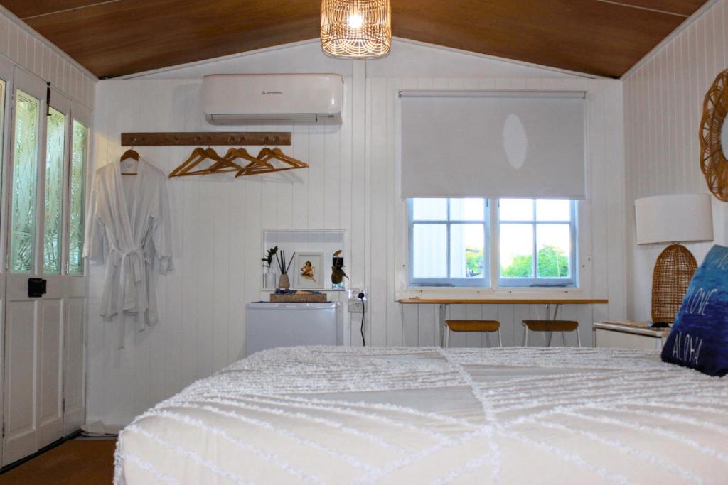 a bedroom with a white bed and two windows at The Bunkhouse in Exmouth