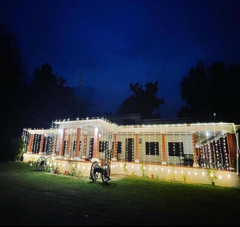 un grand bâtiment avec des lumières devant lui dans l'établissement Maharaja Kothi Resort, Bandhavgarh, à Tāla