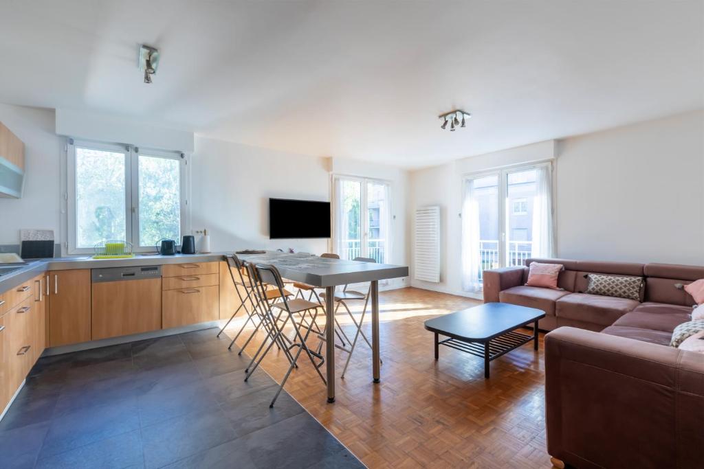 een keuken en een woonkamer met een tafel en een bank bij La Nuit en Rose - 3 chambres - Balcon in LʼHay-les-Roses