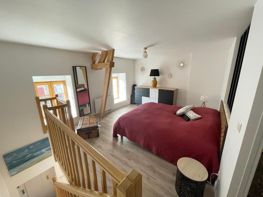 Un dormitorio con una cama roja y una escalera en Petite Maison Cosy - Sérent Centre, en Sérent