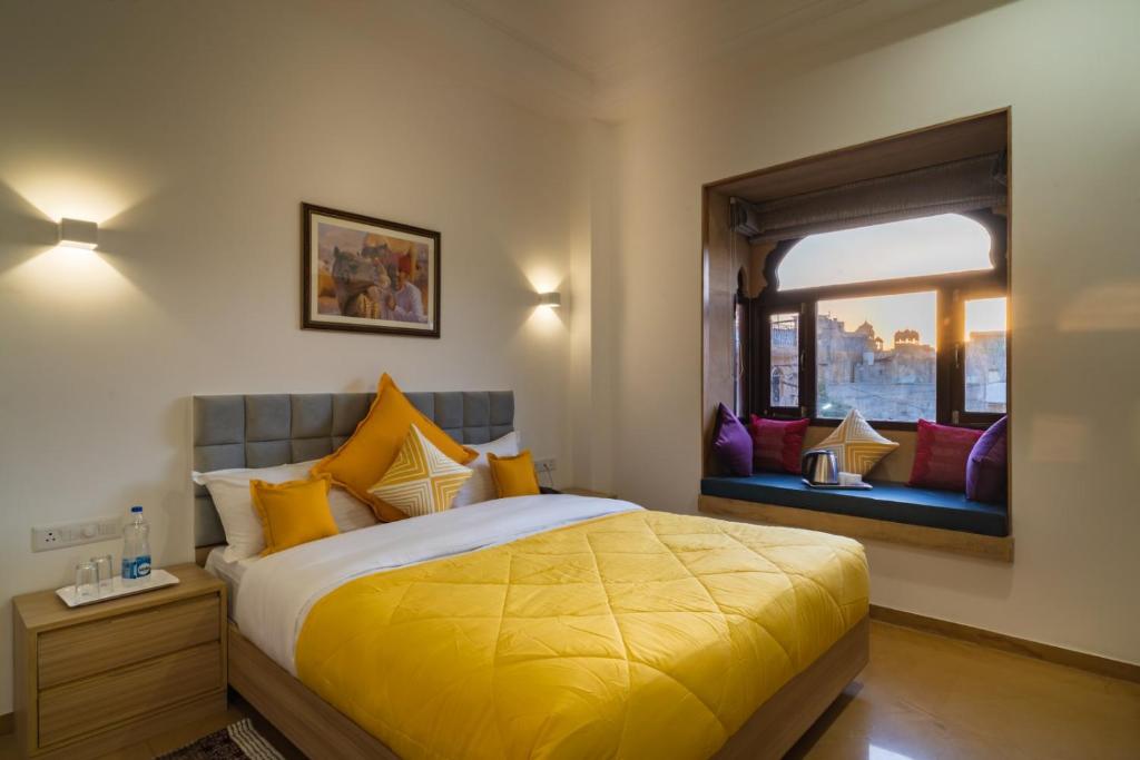 1 dormitorio con 1 cama con edredón amarillo y ventana en Hotel Aradhya Jaisalmer, en Jaisalmer