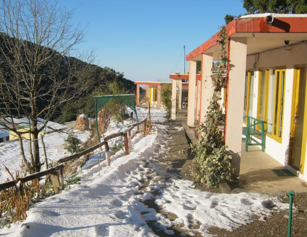 a snow covered path next to a building with a fence at Janardan Resort Pangot, Nainital in Nainital
