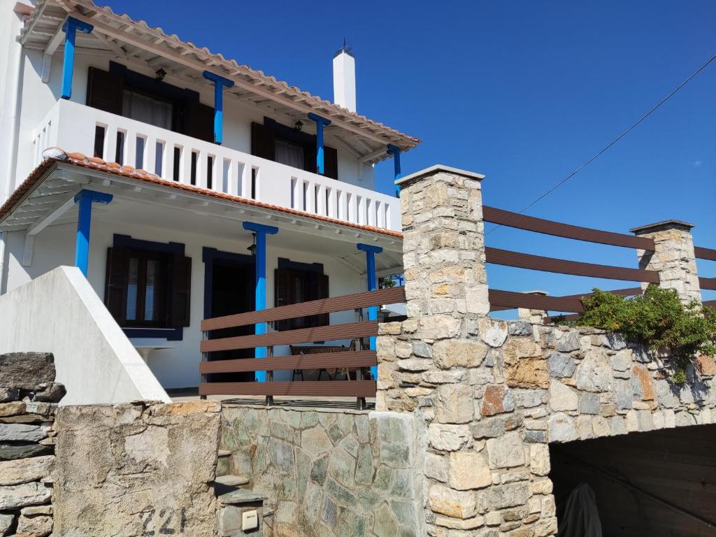 a white house with blue trim and a stone wall at Villa George in Alonnisos