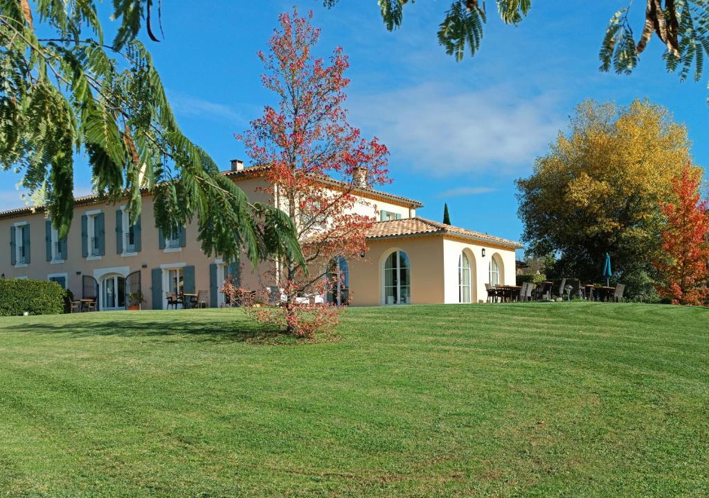 een groot huis op een grasveld met een boom bij Hôtel La Bastide d'Iris in Vagnas