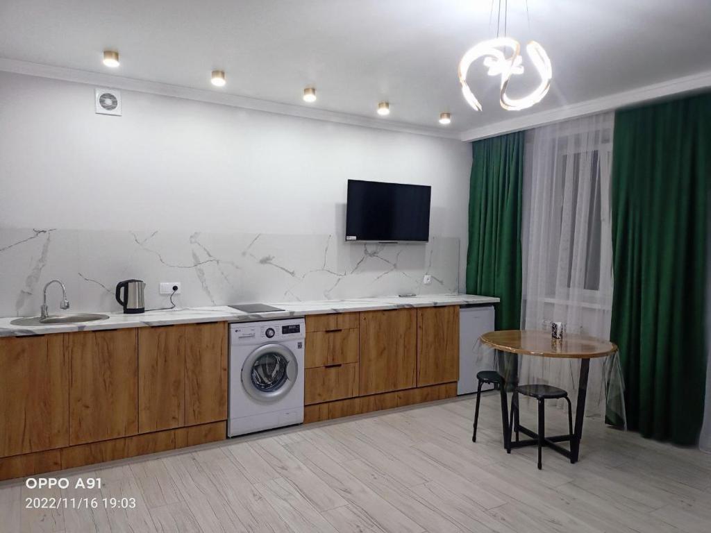 a kitchen with a washing machine and a table at Мухтара Ауэзова 205 in Kokshetau