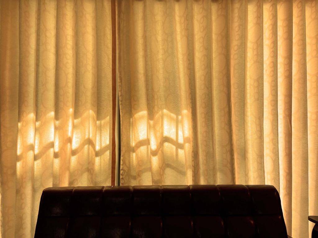 a couch sitting in front of a window with curtains at Lee's Guesthouse in Fengyuan