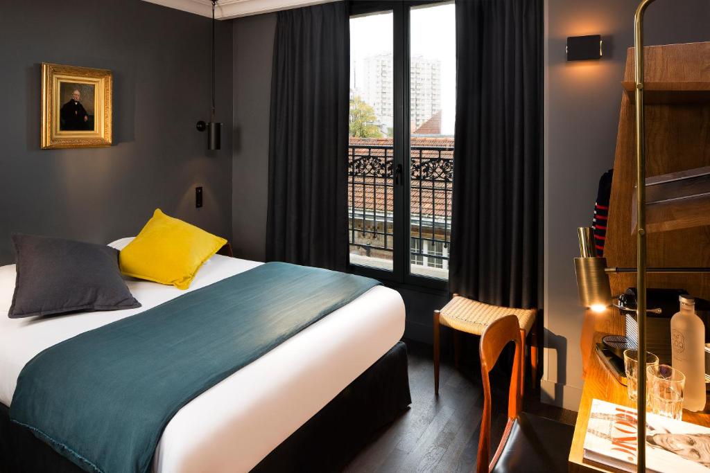 パリにあるCOQ ホテル パリのベッドとバルコニー付きのホテルルーム