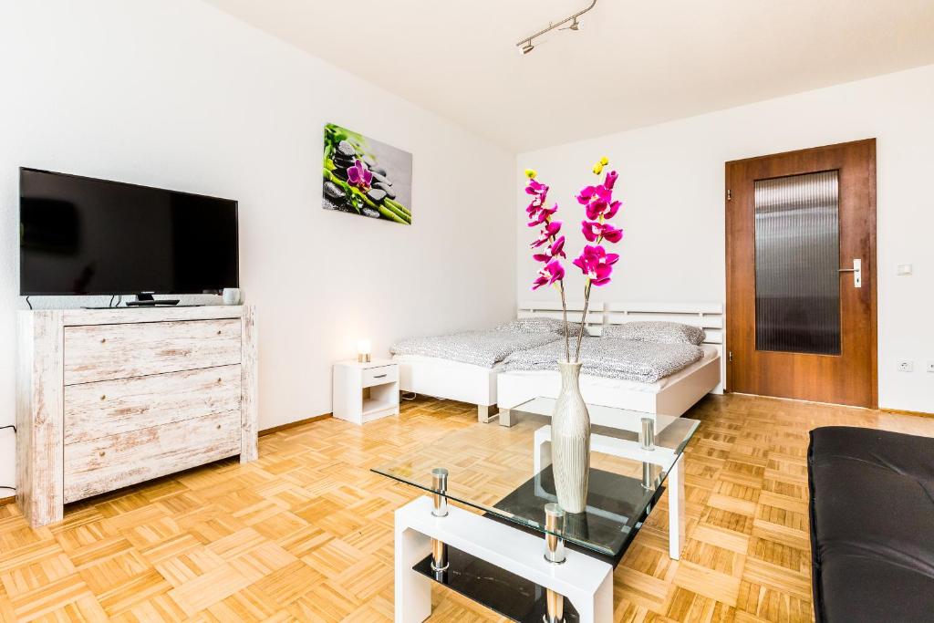 Work & Stay Apartment Monheim في مونهيم: غرفة معيشة مع إناء من الزهور على طاولة زجاجية