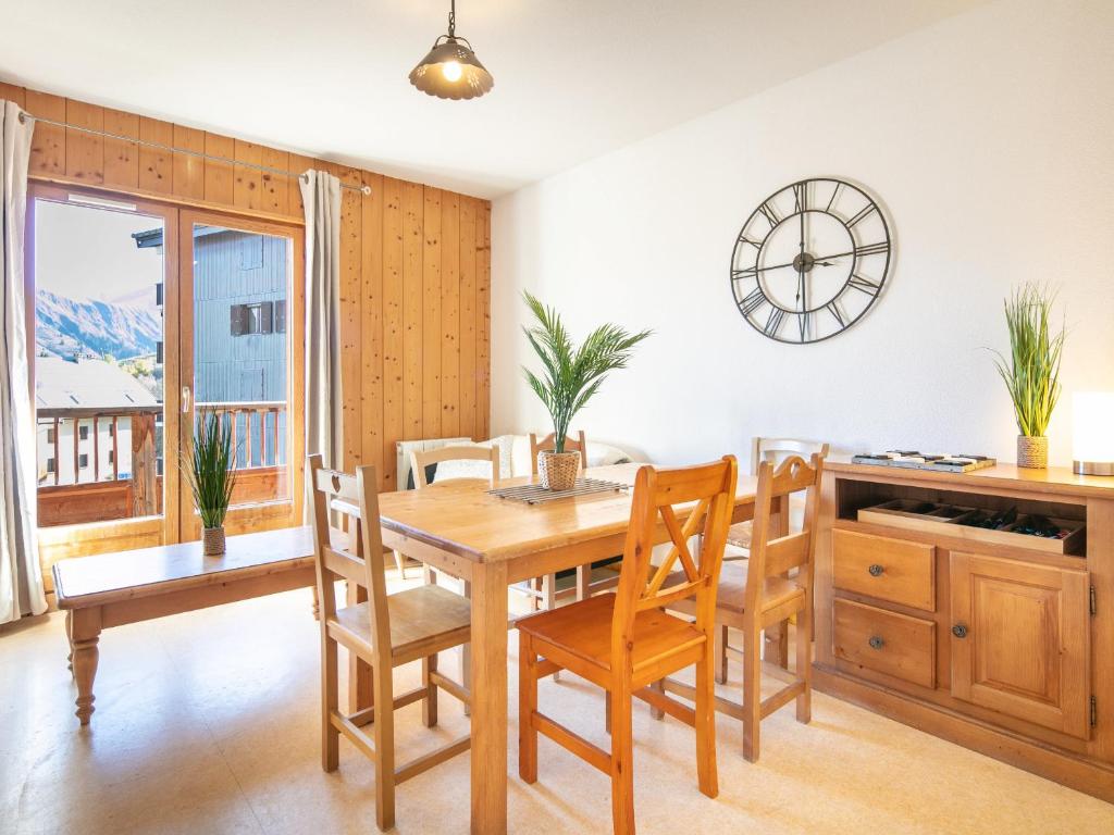uma sala de jantar com mesa e cadeiras e um relógio em Les Bouquetins - 5 - Appart Chaleureux 6 pers em Saint-Sorlin-dʼArves