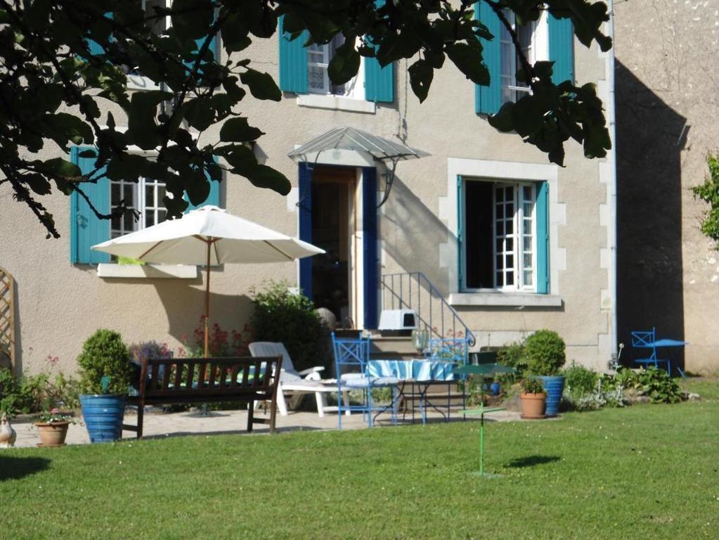 a patio with a table and an umbrella and chairs at La maison bleue in Arquian