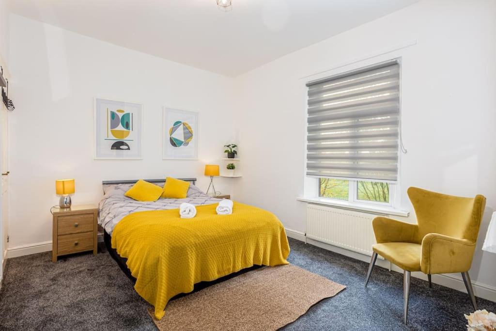 um quarto com uma cama amarela e uma cadeira em Stylish 3 Bedroom Central Property em Newcastle under Lyme