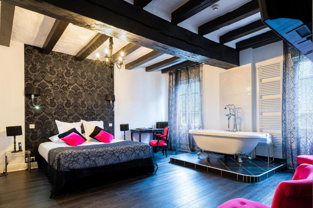 Schlafzimmer mit einem Bett, einer Badewanne und einer Badewanne in der Unterkunft Logis Hotel Restaurant Le Cheval Blanc in Bléré