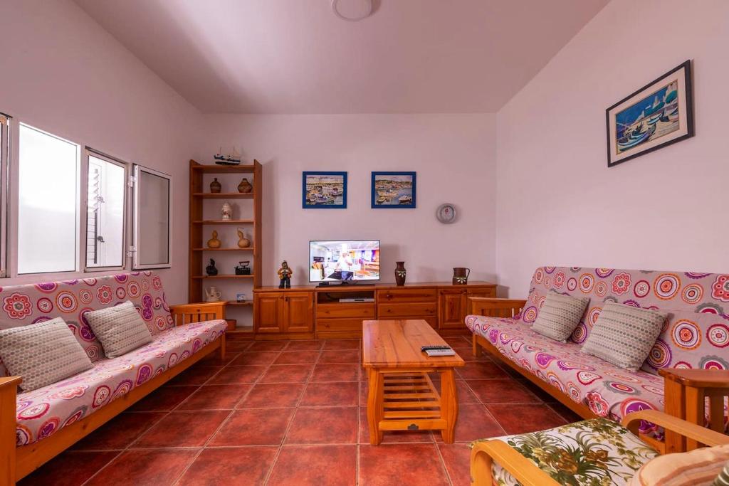 uma sala de estar com dois sofás e uma televisão em 3 bedrooms house at Los Caserones 50 m away from the beach with enclosed garden and wifi em Las Marciegas