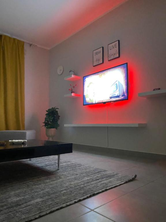 een woonkamer met een tv aan een muur met rode verlichting bij شروق المدينة - مدينة الملك عبدالله الاقتصادية in King Abdullah Economic City