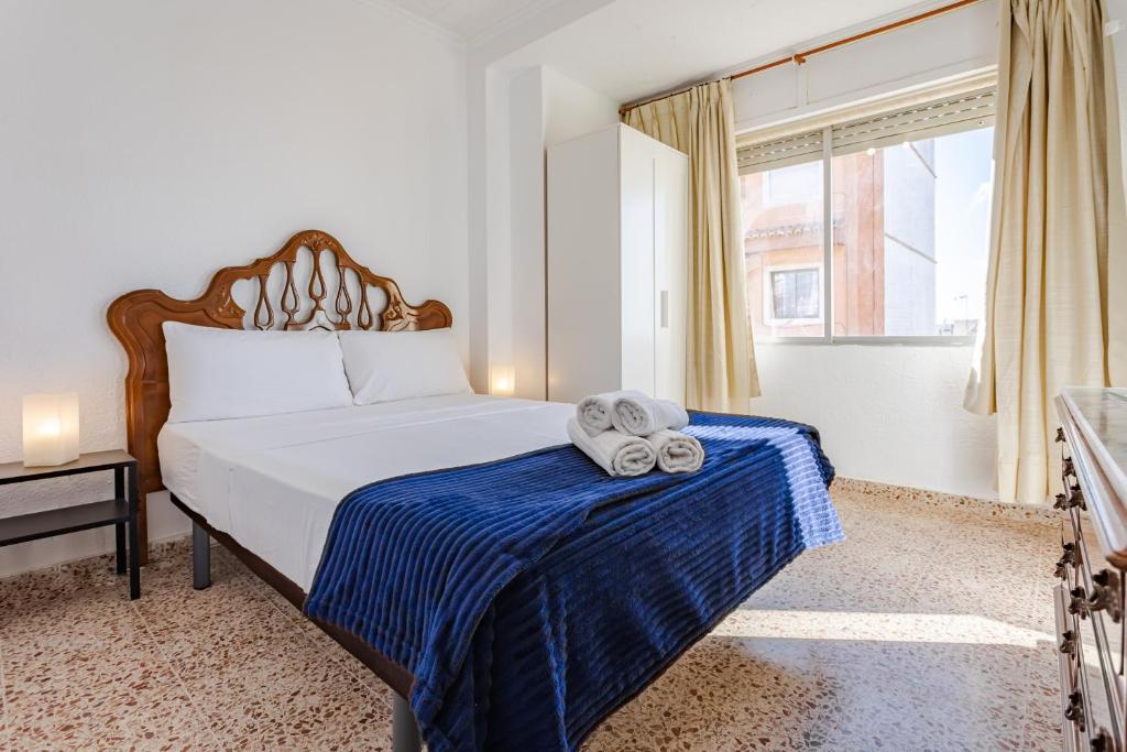1 dormitorio con 1 cama con manta azul y ventana en Town center Apartment El Perello Valencia, en Valencia