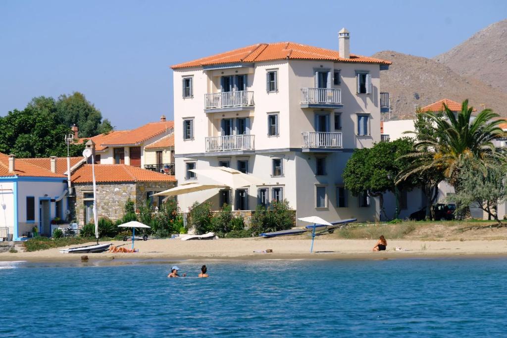 ein Gebäude am Strand mit Schwimmern im Wasser in der Unterkunft Limnos Experience in Mirina