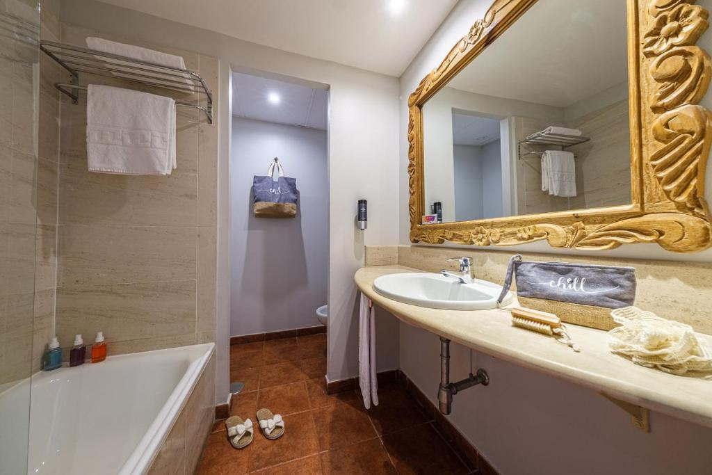 Un baño con bañera, lavabo y espejo. en Estival Islantilla, en Islantilla