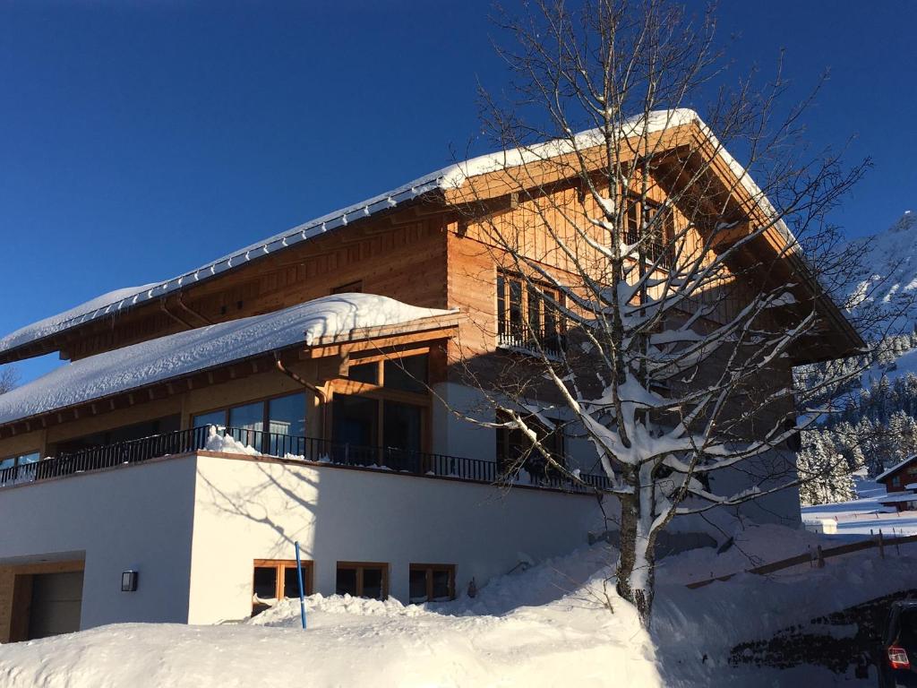 een gebouw in de sneeuw met een boom voor de deur bij Alpenchalet Iseler in Oberjoch