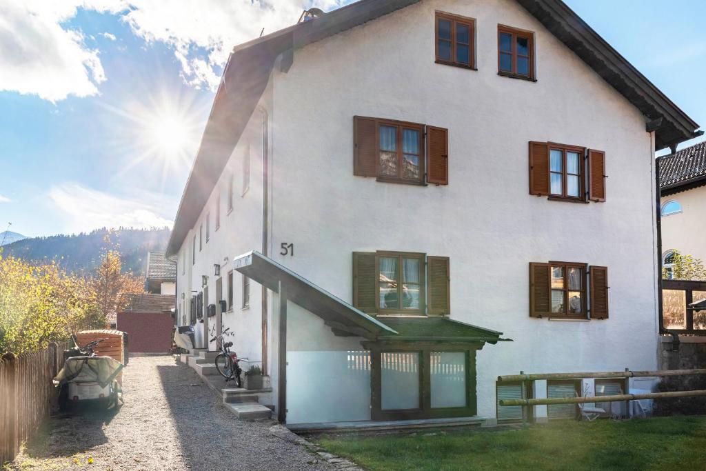 een wit huis met ramen en de zon op de achtergrond bij Höllental 51 in Garmisch-Partenkirchen