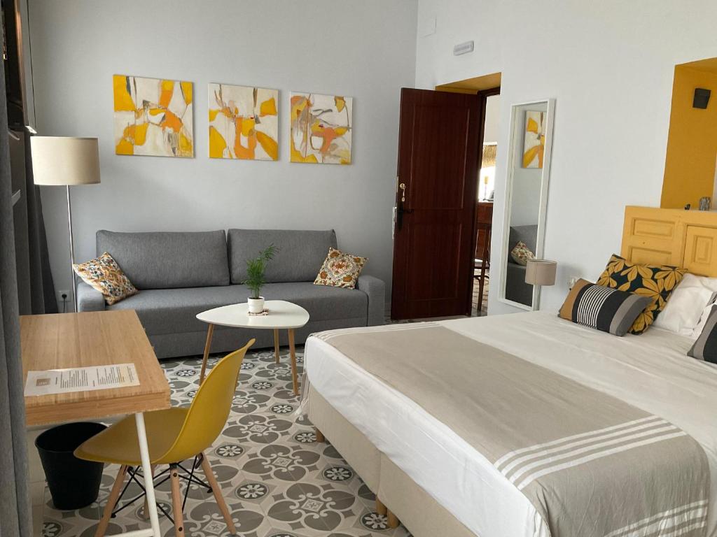 um quarto com uma cama, um sofá e uma mesa em Casa de las Especias Hotel Boutique em Sanlúcar de Barrameda