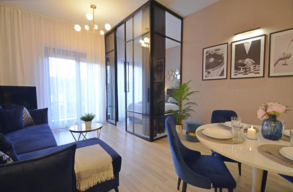 een woonkamer met een tafel en blauwe stoelen bij Osiedle Platan - Apartamenty Bryza - Centrum in Świnoujście