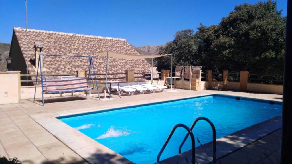 - une piscine avec un banc à côté d'une maison dans l'établissement Magnífico chalet entre Sierra Nevada y Granada, à Dúdar