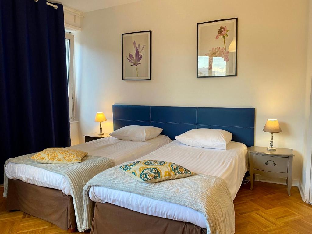 two beds in a room with two tables and two lamps at Appartement Gare Strasbourg Parking in Strasbourg