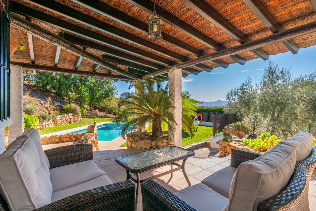 eine Terrasse mit Stühlen, einem Tisch und einem Pool in der Unterkunft El Chorro Villas Casa Buganvilla in El Chorro