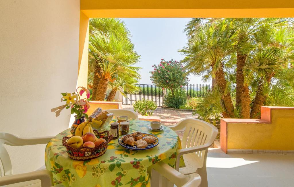 a table with a bowl of fruit on it with palm trees at Baiarenella Residence in Sciacca