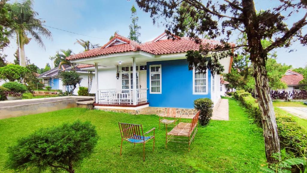 une maison bleue avec deux chaises dans la cour dans l'établissement Sukanagalih Resort by Ruang Nyaman, à Cimacan