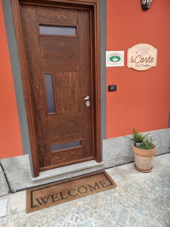 a wooden door with a welcome mat in front of a house at La Corte B&B in Candiolo