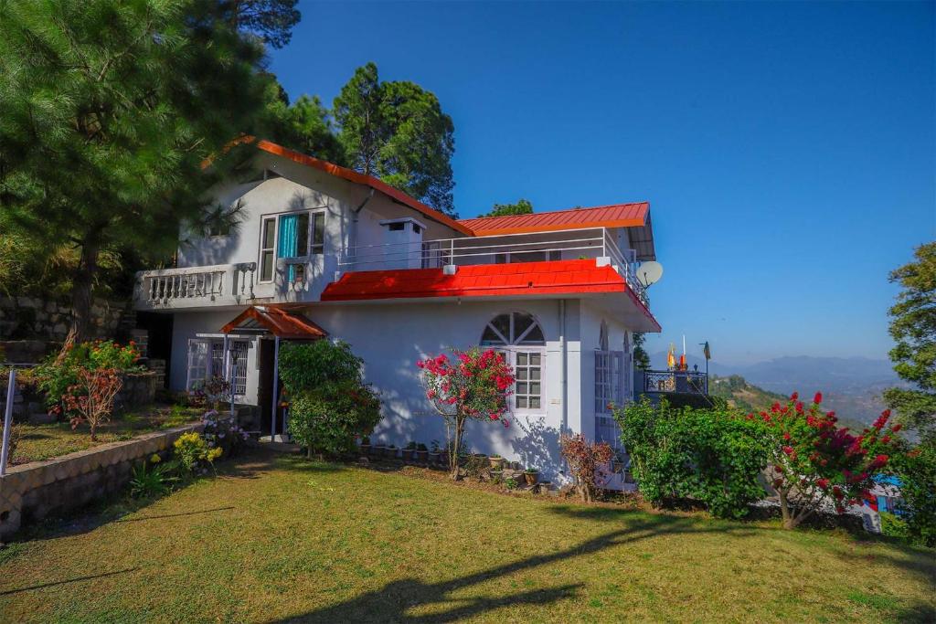 a white house with a red roof and a yard at StayVista at Misty Mountains Cottage in Kasauli